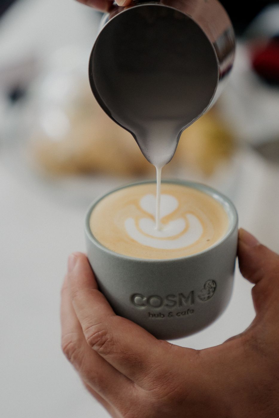 Cafea latte cu desen în spumă, într-o cană COSMO Hub & Cafe