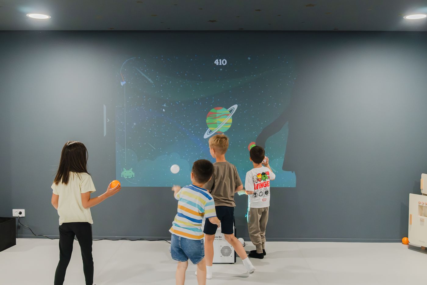 Copii jucând un joc interactiv, proiectat pe perete